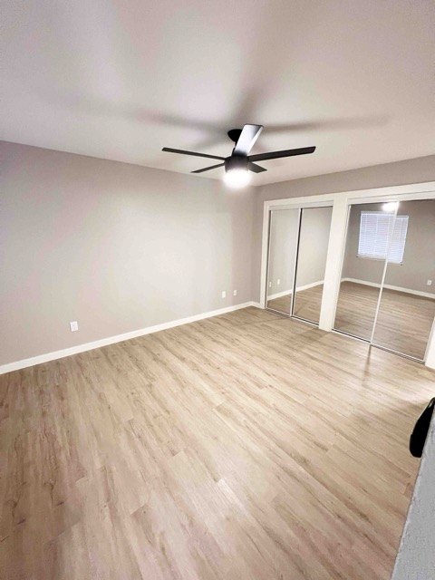 Bedroom with a ceiling fan and mirrored closet doors